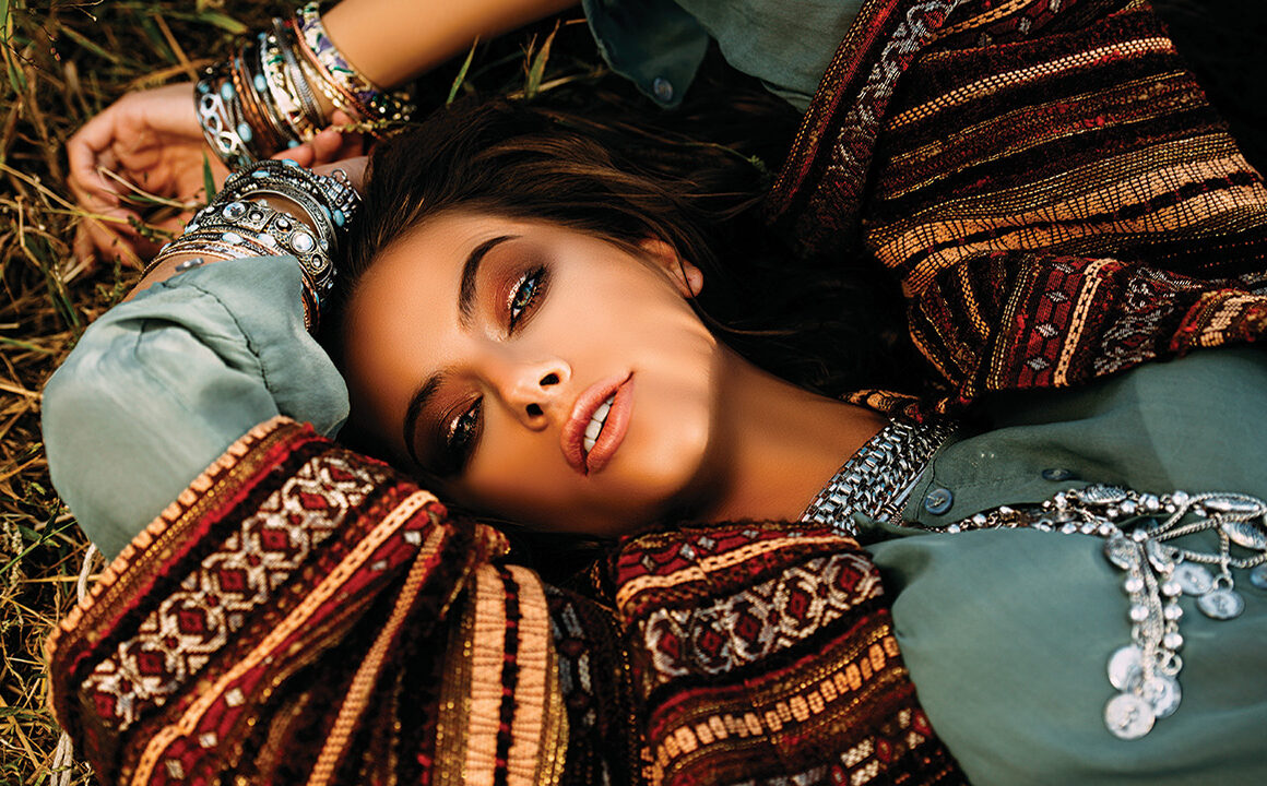 Beautiful hippie girl lying in a grass. Modern boho style. Beauty, fashion,